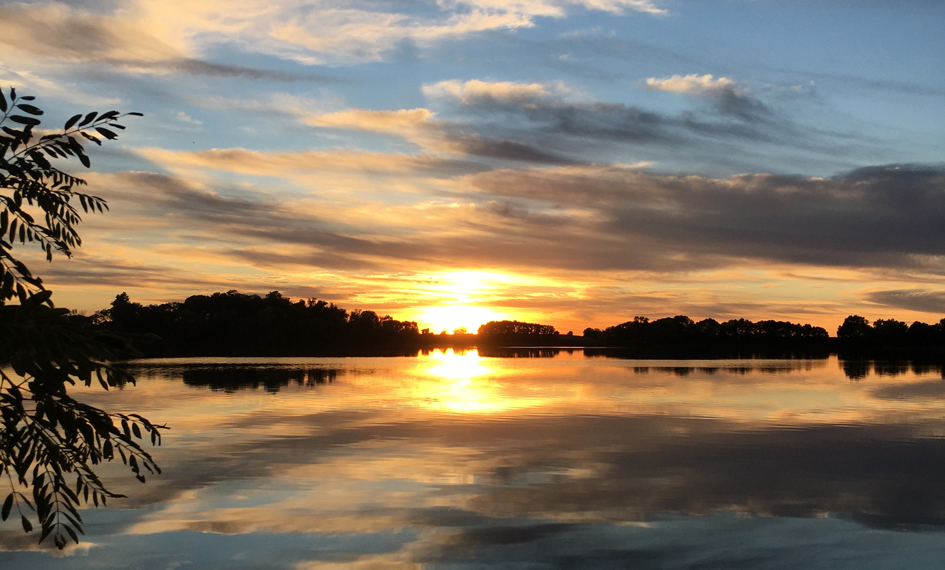 sunset over a glassy lake with the sky reflected in the water
